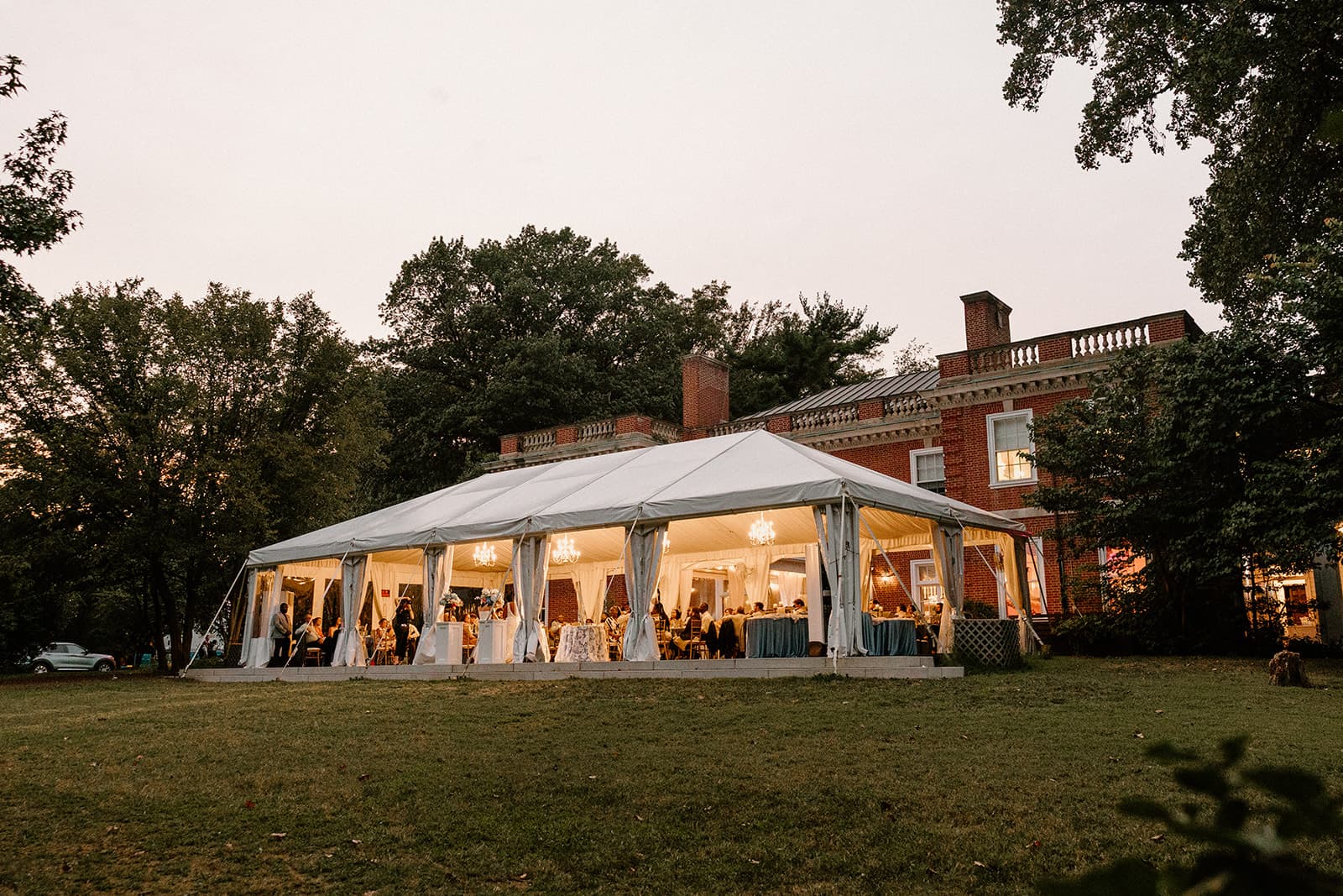 Woodend Sanctuary event tent with lights on at dusk